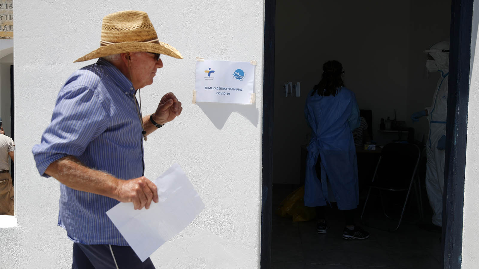 אזרח יווני בכניסה למרפאה של שירות הבריאות הממלכתי באי פולגנדרוס, בה מתבצעות בדיקות קורונה. (צילום: AP Photo/Thanassis Stavrakis)