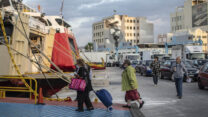 נוסעות עולות למעבורת בנמל פיראוס ביוון. (צילום: AP Photo/Petros Giannakouris)
