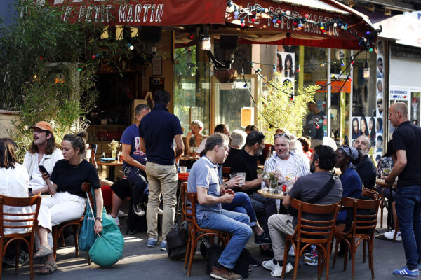 אנשים יושבים בשולחנות מחוץ לבית קפה בפריז (AP Photo/Thibault Camus)