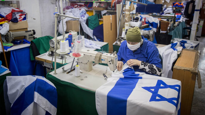 עובדת עם מסכה נגד קורונה במפעל לייצור דגלים, לקראת יום העצמאות. (צילום: יונתן זינדל/פלאש90)