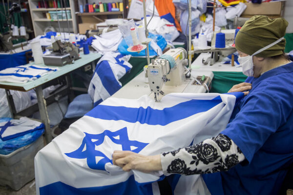 עובדת עם מסכה נגד קורונה במפעל לייצור דגלים, לקראת יום העצמאות. 27 באפריל. (צילום: יונתן זינדל/פלאש90)