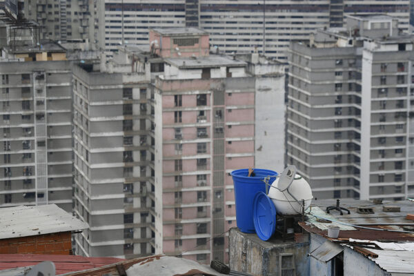 קארקס, ונצואלה: אדם מנקה מכל מים על גג ביתו בשכונת סן אגוסטין. 17 במאי 2020 (AP Photo/Matias Delacroix)