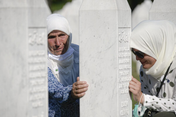 אישה נשענת על קבר סמוך לעיירה סרברניצה בבוסניה, ביום לציון 25 לטבח שאירע בעיירה. (צילום: AP Photo/Kemal Softic)