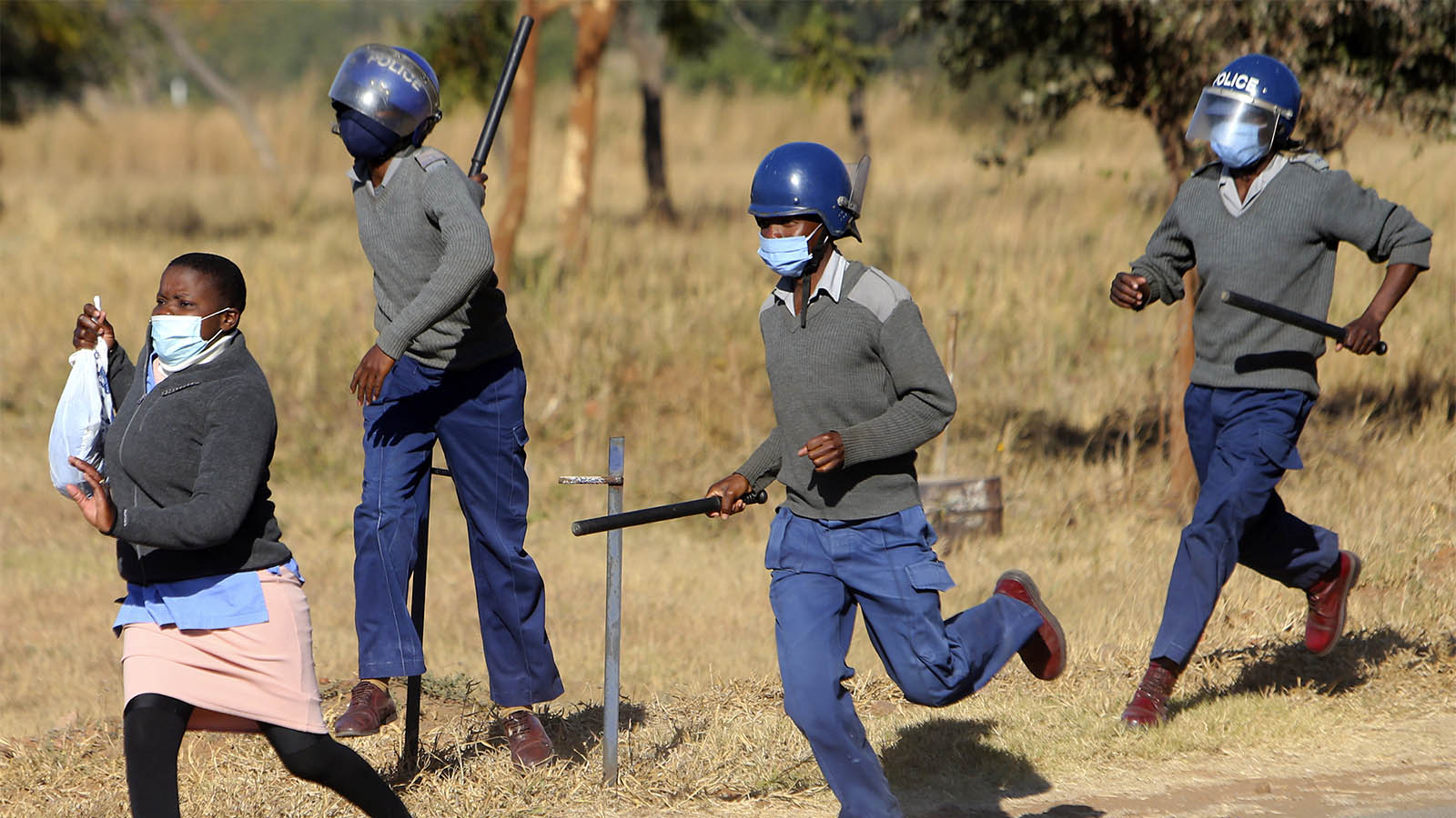 שוטרים רודפים אחרי אחות בית חולים ממשלתי בזימבבואה במהלך הפגנת אחיות בדרישה לשיפור תנאי עבודתן. 6 ביולי (AP Photo/Tsvangirayi Mukwazhi)