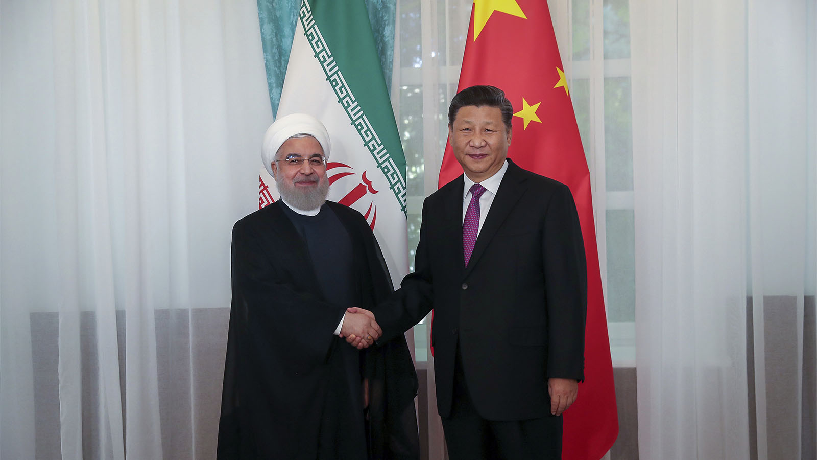 נשיא סין, שי ג'ינפינג לוחץ את ידיו של נשיא איראן חסן רוחאני. ה-14 ביוני 2019 (Iranian Presidency Office via AP)