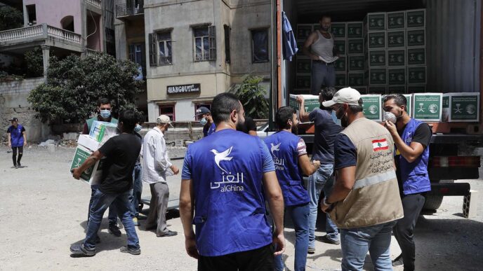 אנשי עמותת אל-חינה מחלקים מארזי מזון לנזקקים בקרבת זירת הפיצוץ בנמל ביירות. (צילום: AP Photo/Hussein Malla)