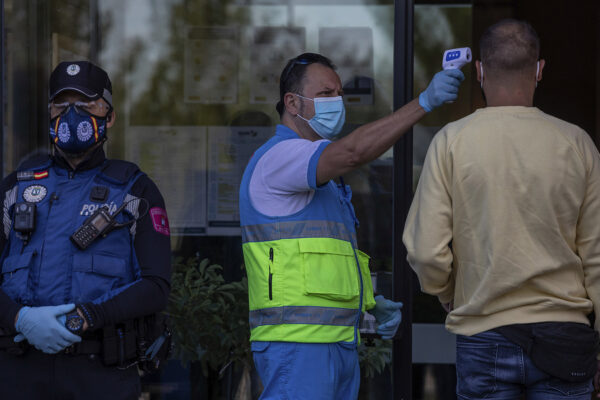עובד בריאות של שירותי חירום במדריד מודד לאיש חום לפני ביצוע בדיקת קורונה. 29 בספטמבר 2020. (צילום: AP Photo/Bernat Armangue)