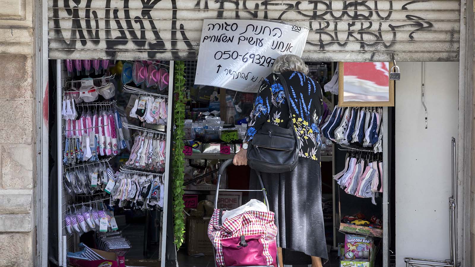אישה מבוגרת בפתח חנות סגורה בגלל הסגר (צילום: נתי שוחט/פלאש90)
