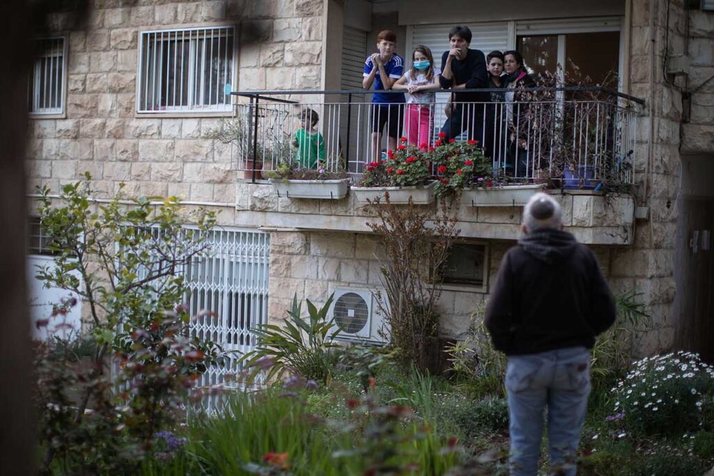 A quarantined family talks to a friend from their apartment balcony, Jerusalem, April 2, 2020. (Photo:Hadas Parush/Flash90)