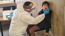 יואב שוורץ (משמאל), עובד מד"א מגבעת שמואל, עורך בדיקת קורונה לתלמיד בבית ספר בגבעת שמואל, כחלק מניסוי בדיקות לתלמידים (צילום: דפנה איזברוך)