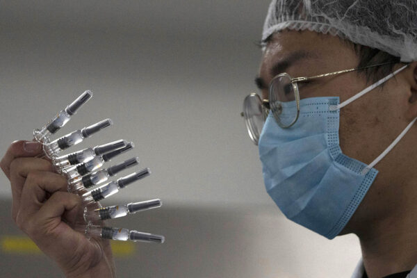 עובד בודק מזרקים לחיסון נגד הנגיף קורונה בבייג'ינג, סין (צילום:AP/Ng Han Guan)