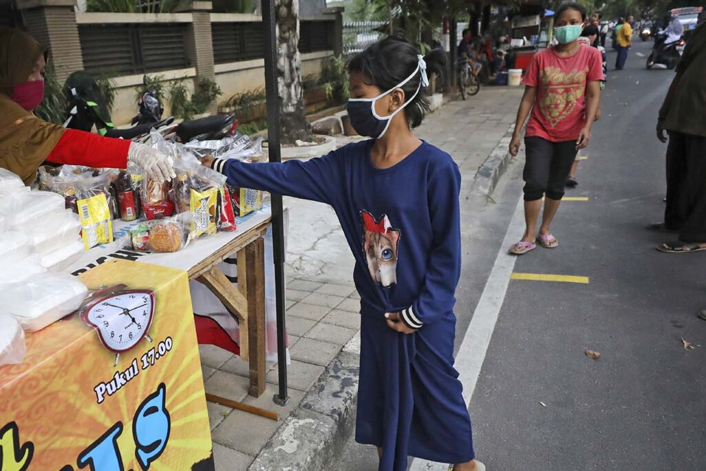 ילדה בג'קרטה, אינדונזיה מקבלת איפטאר שנתרם, ארוחת הערב איתה מוסלמים מסיימים את צום הרמדאן היומי שלהם עם השקיעה. (צילום: AP/Dita Alangkara)