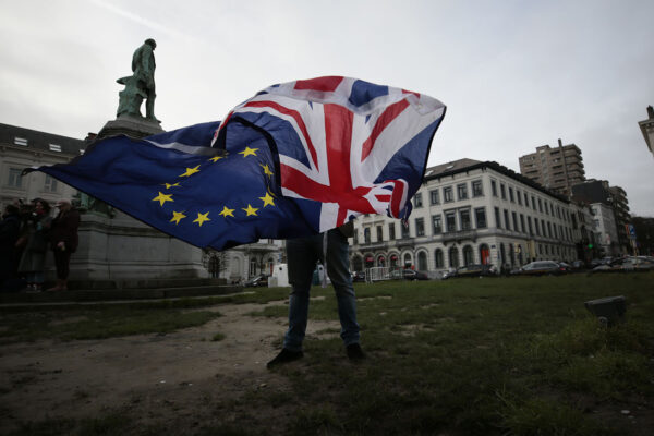 אדם מנופף בדגלי בריטניה והאיחוד האירופי מחוץ למטה האיחוד בבריסל, 30 בינואר 2020 (צילום: AP Photo/Virginia Mayo, File)
