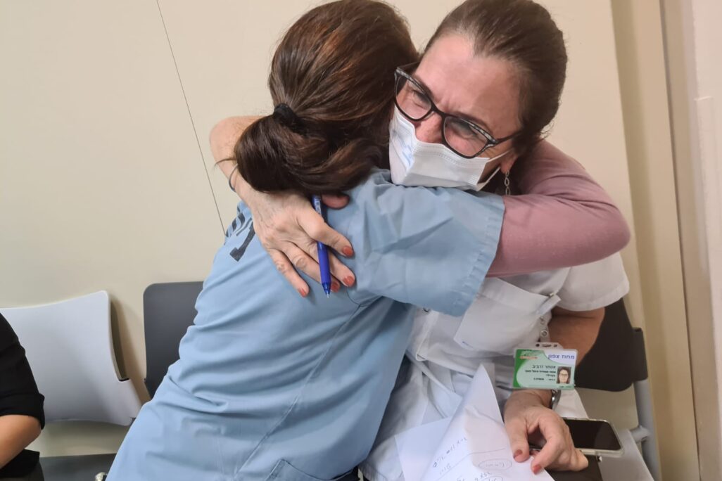 האחות אסתי זרביב, מנהלת מוקדי החיסונים של כללית בצפון, מתחבקת עם עמיתה לעבודה במוקד החיסונים בטבריה, ביום הראשון להפעלתו, 22 בדצמבר 2020 (צילום: דפנה איזברוך)