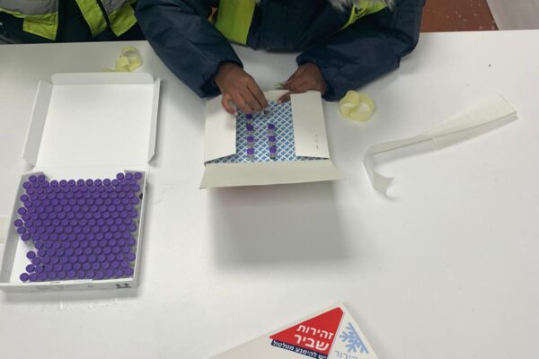 עובדי חברת סלא מפרידים את חיסוני פייזר למארזים קטנים, במחסן מקורר (צילום: משרד הבריאות)