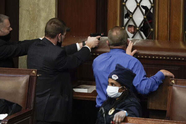 שוטרים עם אקדחים שלופים מול תומכי דונלד טראמפ  שמנסים לפרוץ לאולם בית הנבחרים. (צילום: (AP Photo/J. Scott Applewhite