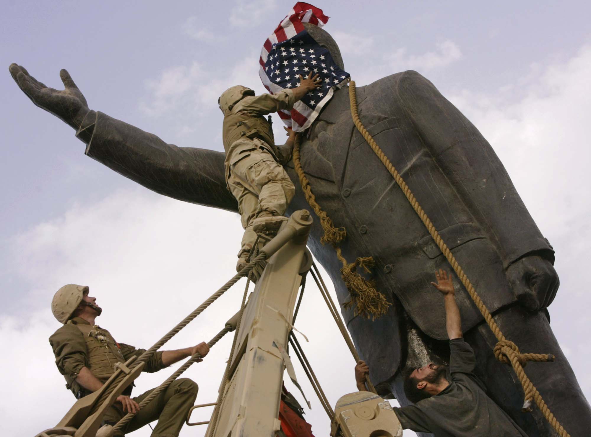 אזרחים עיראקים וחיילים אמריקאים מפילים את פסלו של סדאם חוסיין במרכז בגדאד, 2003 (צילום: (AP Photo/Jerome Delay, File)