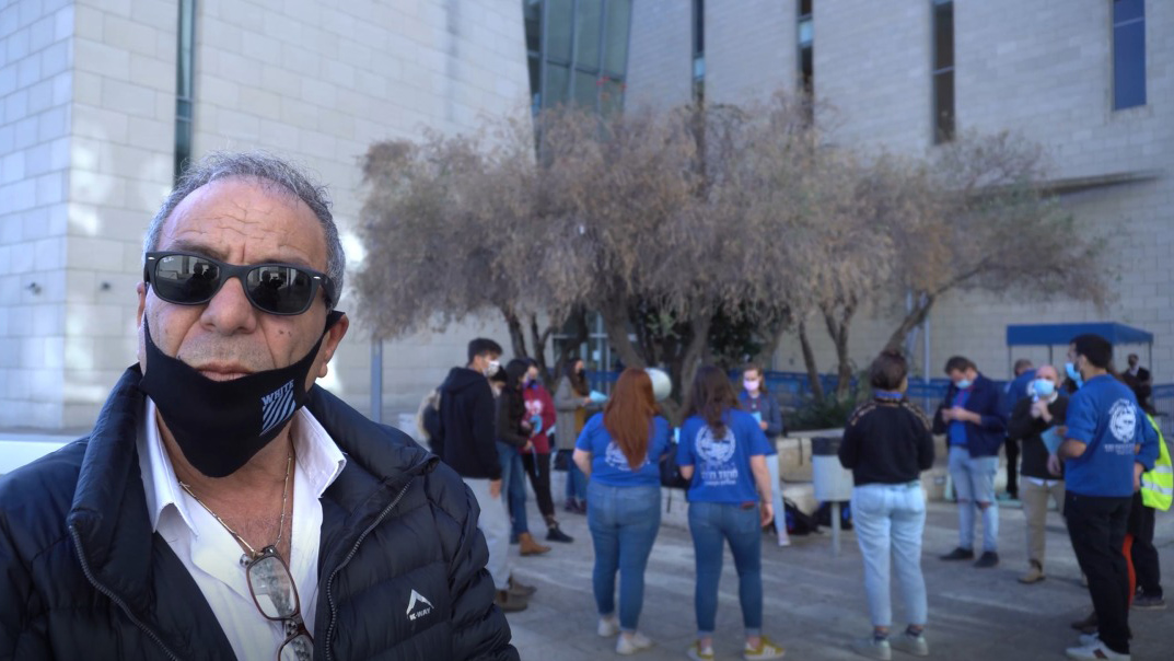 עו&quot;ד אברהם אלוק מחוץ לבית הדין בחיפה. מאחוריו חניכי הנוער העובד והלומד מפגינים (צילום: יותם טירקל)