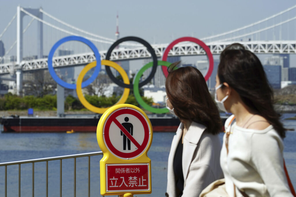 נשים בטוקיו על רקע הטבעות האולימפיות  (צילום: AP Photo/Eugene Hoshiko)