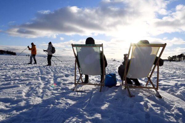 אנשים נהנים ממזג האוויר שטוף השמש על הקרח על קו החוף של הלסינקי, פינלנד, פברואר 14, 2021. (צילום: Lehtikuva/Jussi Nukari via REUTERS)