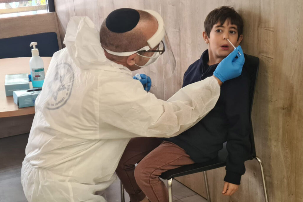 Yoav Schwartz (left), Magen David Adom employee from Givat Shmuel, conducts a coronavirus test on a student at a school in Givat Shmuel, as part of the testing program. (Photo: Dafna Eisbruch)