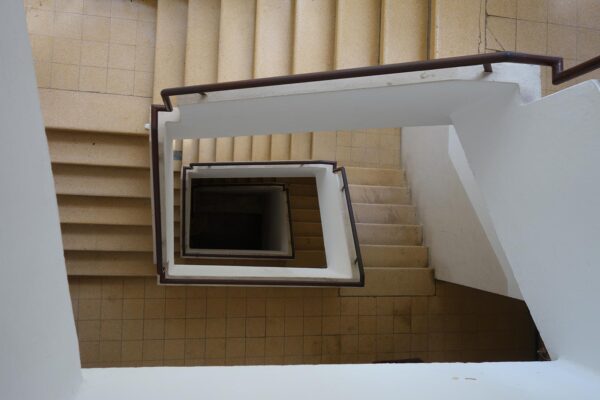 חדר המדרגות בבניין ברחוב מסדה, חיפה. אדריכלים: בנימין אוראל ויחזקאל זוהר. חדרי המדרגות של ימינו סגורים בחדרים אטומים, מאחורי דלתות כבדות ומוארים בתאורה חיוורת. לא תמיד זה היה כך (צילום: מיכאל יעקובסון)
