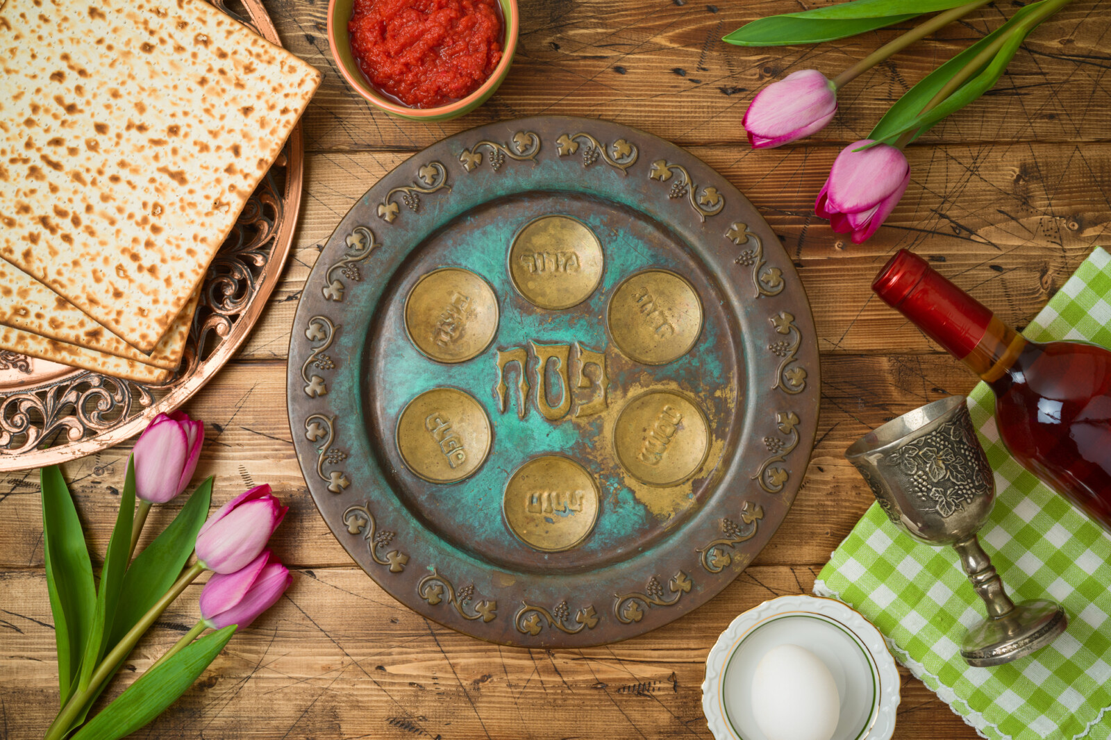 Jewish holiday Passover background with matzo, seder plate, wine and tulip flowers on wooden table. Top view from above.
   קרדיט: https://depositphotos.com/