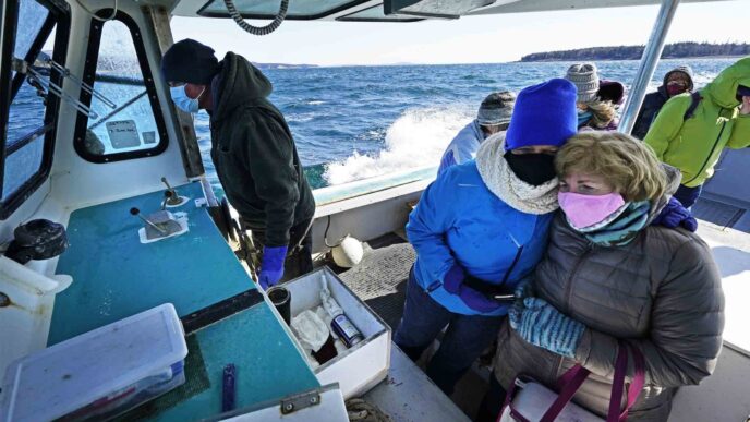 אחיות רפואיות מצטופפות נגד הקור, על גבי סירה לדיג לובסטרים בדרך להקים תחנת חיסון כנגד נגיף הקורונה באיי קרנברי. &quot;יום היסטורי בשביל תושבי האיים&quot;. (צילום: AP Photo/Robert F. Bukaty)