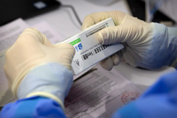 עובד פותח חבילה של החיסון של חברת סינופארם הסינית נגד קורונה. (צילום: AP/Mark Schiefelbein)