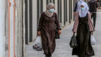 נשים הולכות עם מסכות ברצועת עזה (צילום: עבד אל רחים כתיב/פלאש90)