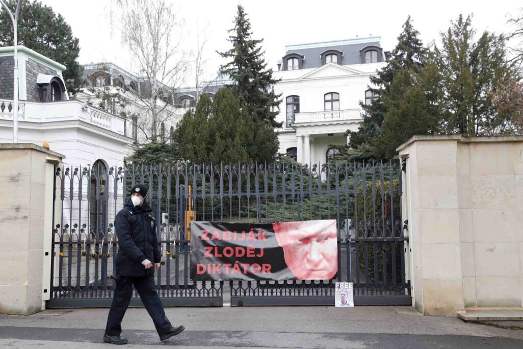 שוטר צועד על פני שלט שהדביקו מפגינים על שער שגרירות רוסיה בפראג. (צילום: AP Photo/Petr David Josek)
