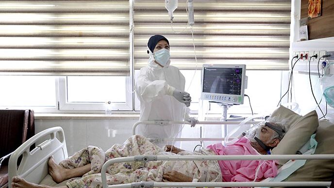 אחות בבית החולים שהדא-א-טג׳ריש מטפלת בחולה קורונה. הלחץ הכלכלי גורם לרבים לוותר על הריחוק החברתי  (AP Photo/Ebrahim Noroozi)