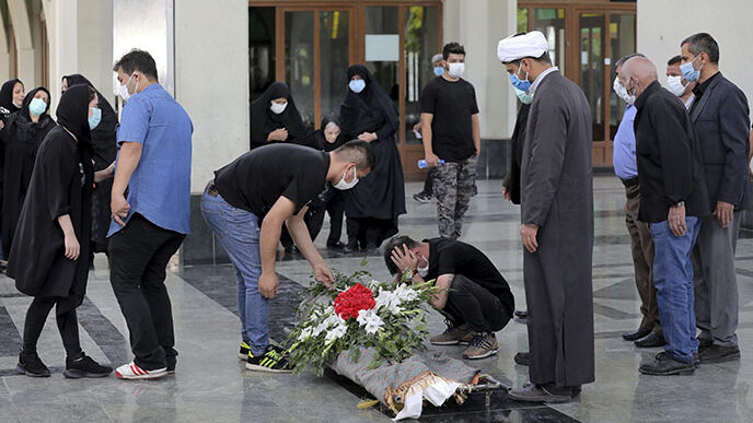 קרובי נפטר מקורונה מתאבלים ליד גופתו בבית העלמין בשט-א-זאהרה מחוץ לטהראן. זרם בלתי נגמר של הלוויות (AP Photo/Ebrahim Noroozi)