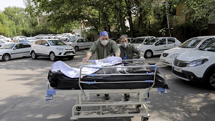 עובדים בבית החולים שהדא-א-טג׳ריש מעבירים גופות נפטרים לחדר המתים. איראן היא המדינה שנפגעה מהקורונה באופן הקשה ביותר במזרח התיכון (AP Photo/Ebrahim Noroozi)