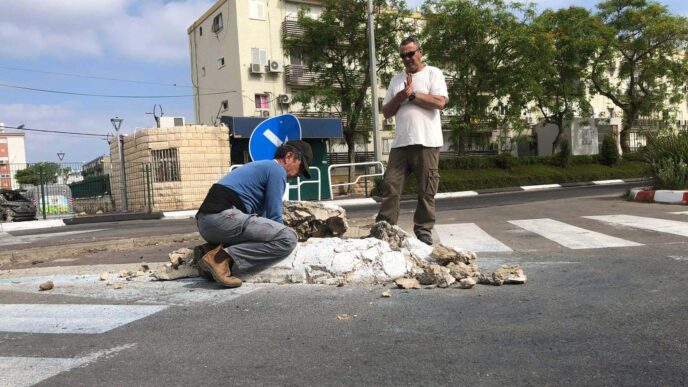 Construction workers attempt to repair a damaged street sign. (Photo: Omer Cohen)