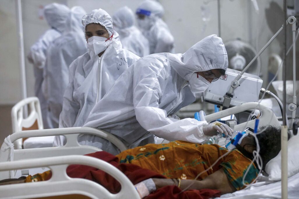 עובד רפואה מנסה ליישר מסכת חמצן של חולת קורונה בבית החולים הזמני במומבאי. (צילום: AP Photo/Rafiq Maqbool)