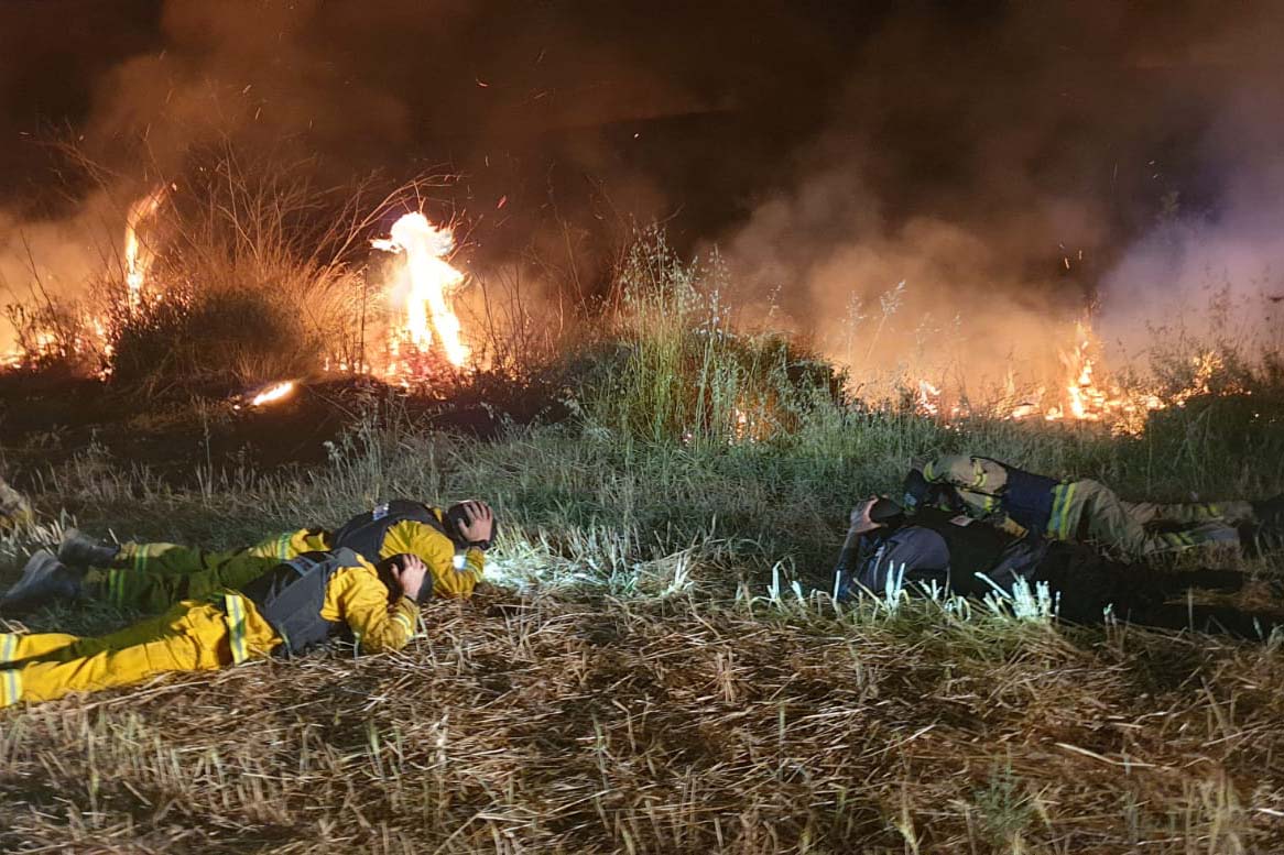 כבאים תופסים מחסה תוך כדי כיבוי שריפה (צילום: תיעוד מבצעי, כבאות והצלה לישראל, מחוז דרום)