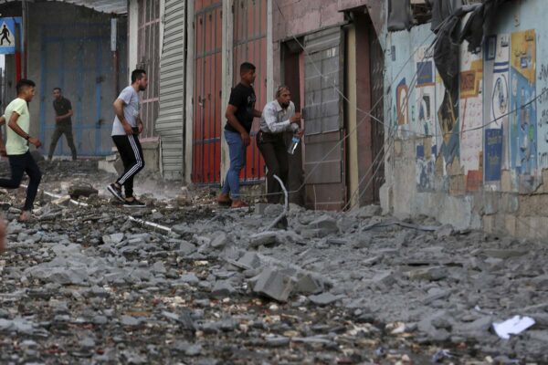 תופסים מחסה ברחוב בעזה במהלך תקיפה ישראלית. "מדינות ערב יצביעו בגוש בצורה ביקורתית ביחס למה שישראל עושה לפלסטינים" (AP Photo/Adel Hana)