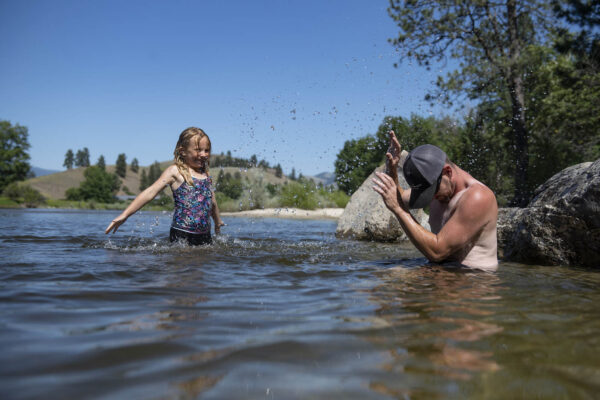 ילדה ואביה מתקררים בנהר "ביטר-רוט" במדינת מונטנה במהלך גל החום(צילום: AP Photo/Tommy Martino)