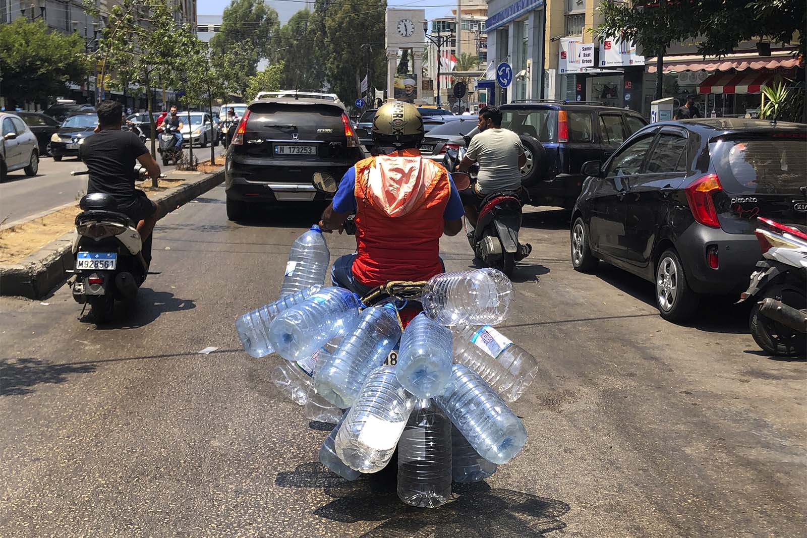 אדם נוסע ברחבות ביירות על קטנוע בדרך למלא בקבוקים בדלק. לבנון, יוני 2021 (צילום: AP Photo/Hussein Malla)