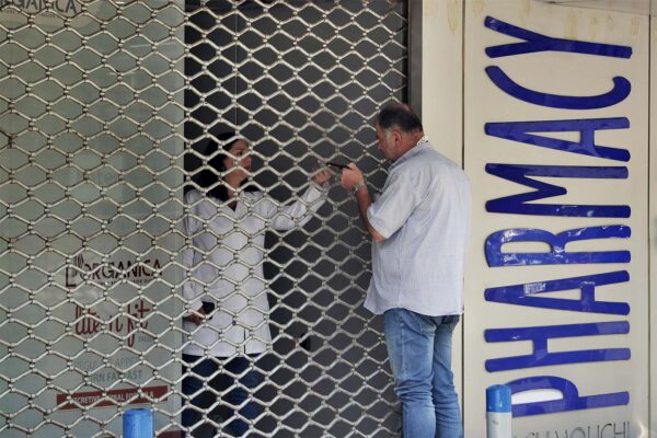 אדם מדבר עם רוקחת בבית מרקחת סגור. בתי המרקחת בלבנון שבתו בגלל מחסור חמור בתרופות יסודיות (צילום: AP Photo/Bilal Hussein, File)