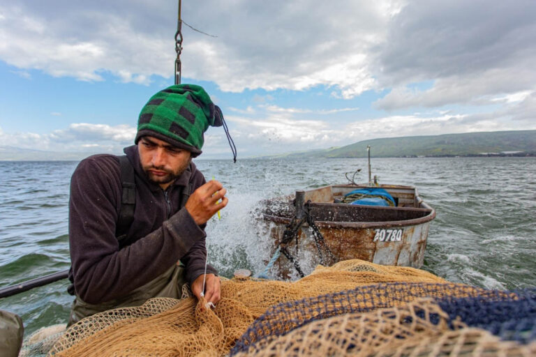 One of the members of the fishing crew repairs a net. (Photo: Micha Hellman)