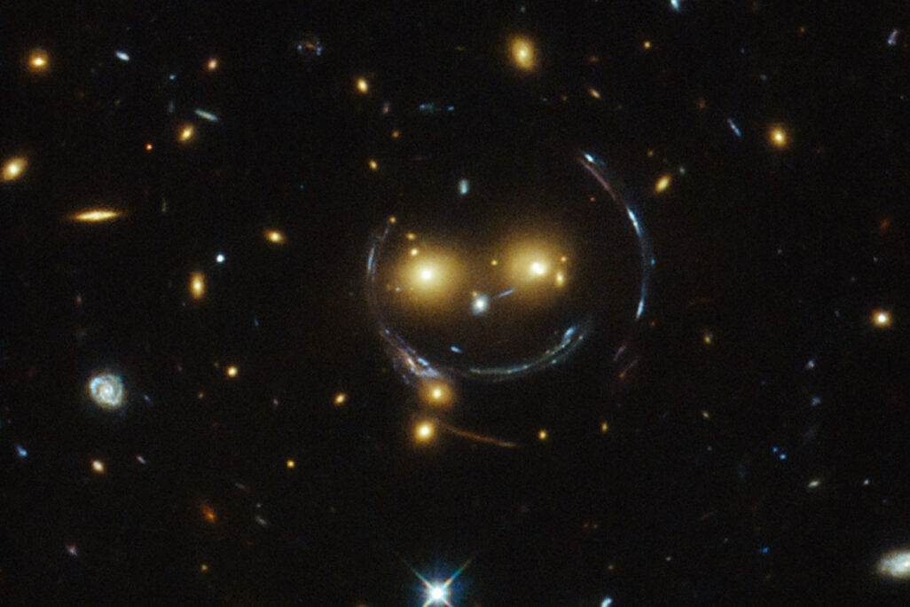 חיוך קוסמי. צביר הגלקסיות SDSS J1038+4849 כפי שצולם על ידי טלסקופ החלל האבל. ה&quot;עיניים&quot; הן זוג גלקסיות בוהקות במיוחד והחיוך נוצר על ידי אפקט &quot;עדשת כבידה&quot; המעקם את האור שעובר דרך הצביר. &quot;חיים פשוטים זה לא מעניין&quot; (צילום: נאס&quot;א)