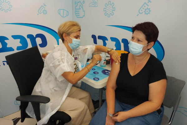 לאורה לודמילה וייסמן מקבלת חיסון במכבי בראשל״צ מידי האחות אולגה גרגורייב (צילום: דוברות מכבי)