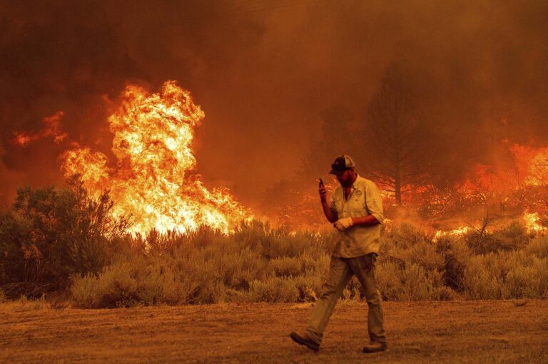 תושב העיירה ג'יינסוויל בקליפורניה מקיים שיחת טלפון בזמן ש'שריפת דיקסי' מתקבלת לביתו. 'שריפת דיקסי' החלה ב-13 ביולי ועדיין משתוללת בקליפורניה. (צילום: AP Photo/Noah Berger)