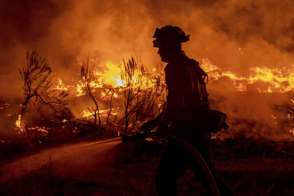 כבאי מרסס מים על אזורים שנפגעו מ'שריפת דיקסי' בקליפורניה. תנאי מזג אוויר קשים באזור מאיימים לסייע בהתפשטות של מספר שריפות בצפון המדינה. (צילום: (AP Photo/Ethan Swope