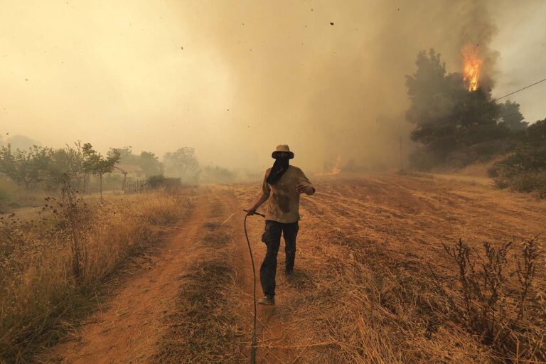 אדם רץ בזמן שריפה בכפר על האי היווני אוויה. גל החום המתמשך במדינה ייבש את היערות והלהבות המשתוללות מאיימות על איזורים מיושבים ועל רשת החשמל. (צילום:AP Photo/Thodoris Nikolaou)