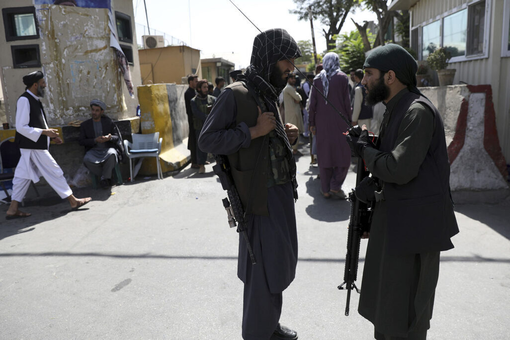 مقاتلو طالبان يقفون أمام البوابة الرئيسية للقصر الرئاسي في كابُل. (تصوير:AP Photo/Rahmat Gul)