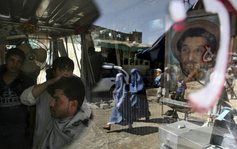 ספר אפגני מספר לקוח במספרה שלו בקאבול, שעל דלתה תמונת דיוקן של גיבור המלחמה האפגני אחמד שאה מסעוד, 29 בספטמבר 2009 (AP Photo/Altaf Qadri)