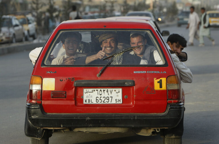 גבר אפגני במושב אחורי של מונית בקאבול, 30 ביוני 2011. אפגנים עניים בדרך כלל חולקים מוניות בשעות העומס. (AP Photo/Gemunu Amarasinghe)